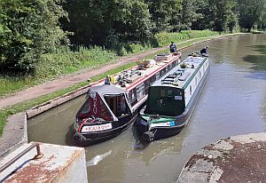 Narrowboats Kairos and Gabriel paired up going into a lock on a wide lock flight.